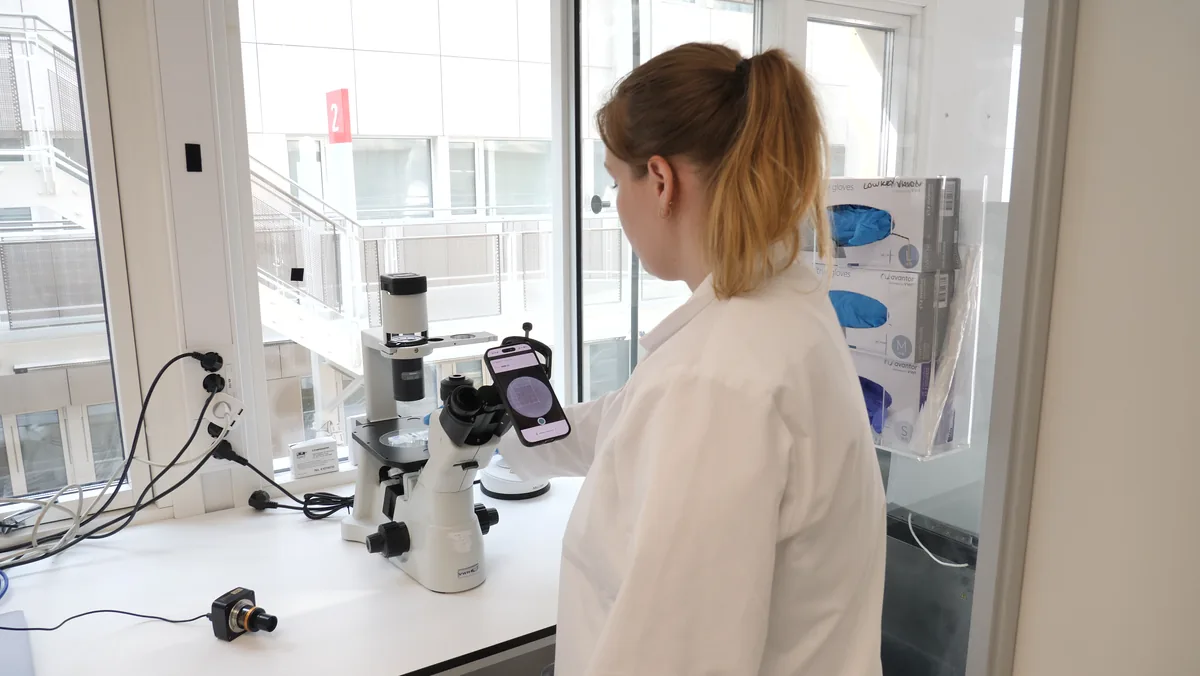 A scientist at the bench counting with CellCount on a phone at the microscope