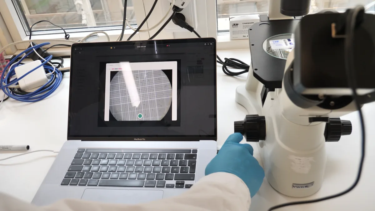 The recommended setup: a camera on the microscope port and the live hemocytometer grid in CellCount on the laptop beside it